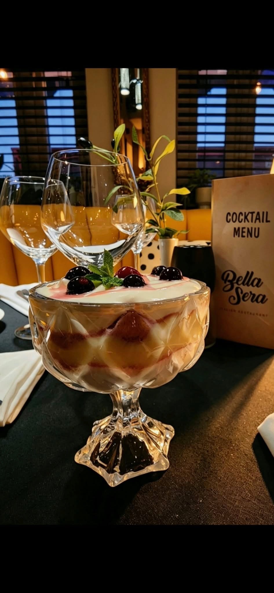 A berry-topped dessert served beside wine glasses