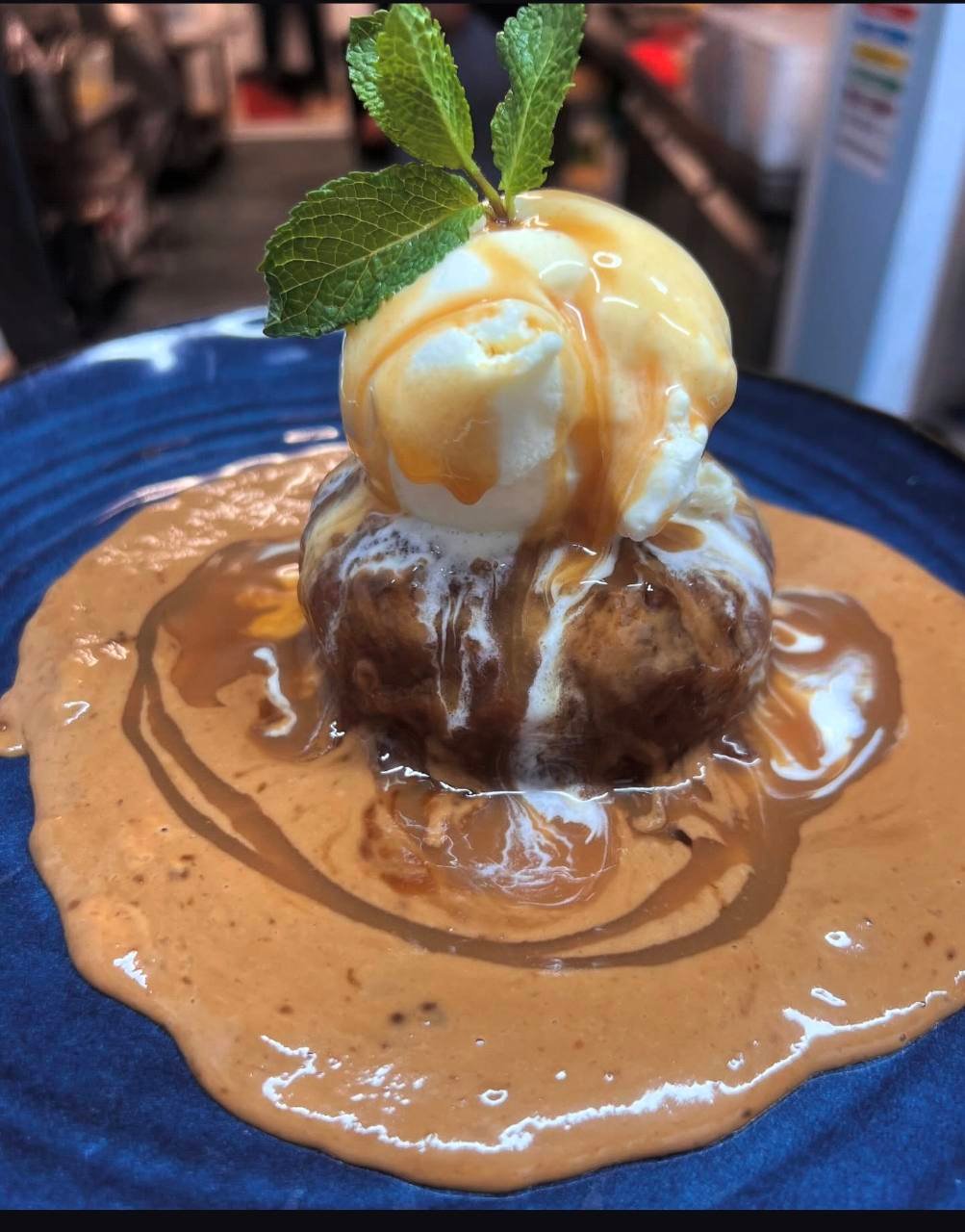 Warm pudding topped with ice cream, caramel sauce and fresh mint
